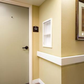 A hallway with a closed door, framed picture, and light switch.