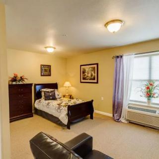 A cozy bedroom with a single bed, a wooden dresser, and soft lighting from lamps.