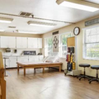 A well-equipped physical therapy room with exercise equipment and therapy tables.