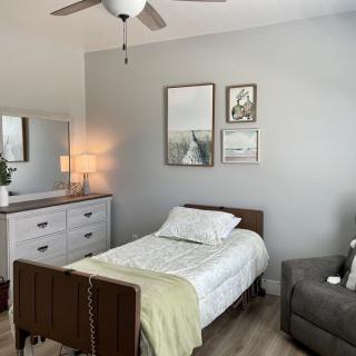 A modern minimalist bedroom with a single bed, dresser, and wall art.