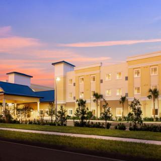 Modern hotel building at sunset with landscaped surroundings.