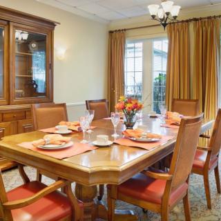 A well-appointed dining room with a wooden table and chairs, complemented by elegant curtains and a chandelier.