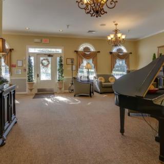 A spacious living room featuring a grand piano, elegant chandeliers, and classic furnishings.