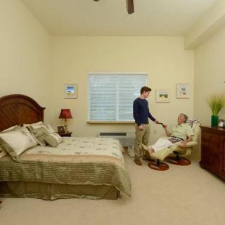 A comfortable bedroom scene with two people engaged in conversation.