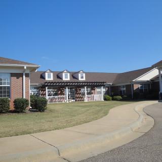 A large residential building with a paved driveway on a clear day.