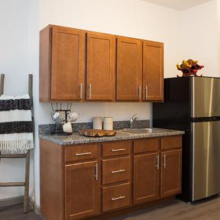 A modern kitchen with wooden cabinets and a stainless steel fridge.