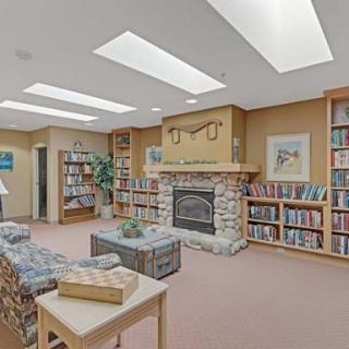 A cozy library with a fireplace, surrounded by bookshelves and comfortable seating.