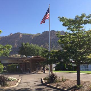 An American flag flying in front of a building with mountains in the background.