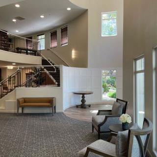 A modern lobby with elegant seating, ample lighting, and a staircase.