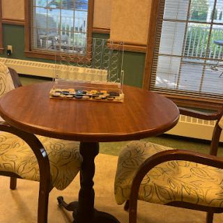 A cozy dining area featuring a wooden table and patterned chairs, illuminated by natural light from the windows.