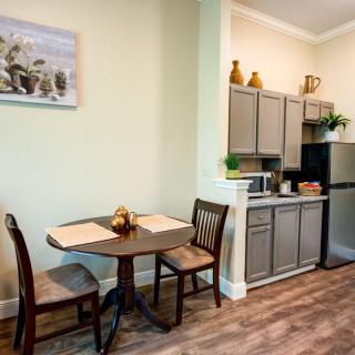 A cozy dining area adjacent to a small kitchen with wooden cabinetry and modern appliances.
