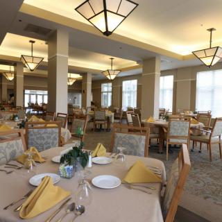 Elegant dining room with neatly arranged tables and chairs, featuring stylish lighting and folded napkins.