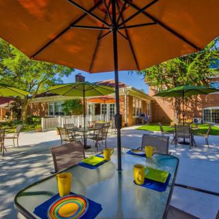 An inviting outdoor patio area with tables set for dining under colorful umbrellas.