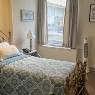 A cozy bedroom with a single bed, a bedside lamp, and a window with curtains.