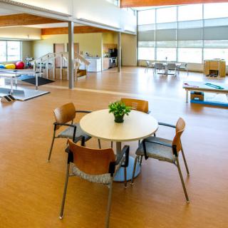 A spacious and well-lit interior of a rehabilitation center, featuring a simple table surrounded by chairs.