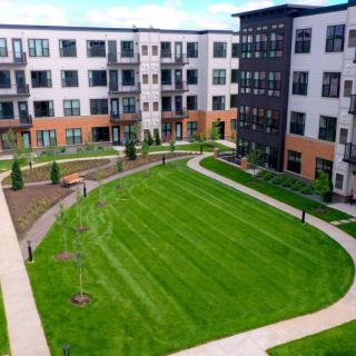 A modern apartment complex with a spacious green lawn in the courtyard.