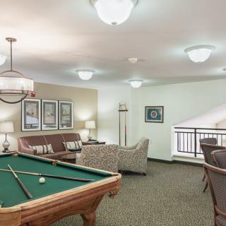 A cozy game room featuring a billiard table, seating area, and modern lighting.
