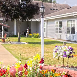 A well-maintained yard with colorful flowers and a classic lamp post in front of a house.