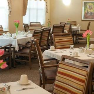 A cozy dining room with neatly arranged tables and chairs, adorned with flowers.