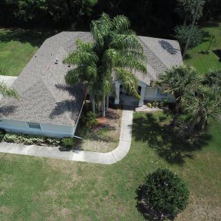Aerial view of a residential house surrounded by trees and a well-maintained yard.