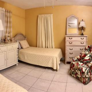 A cozy bedroom with twin beds, a dresser, and a floral armchair.