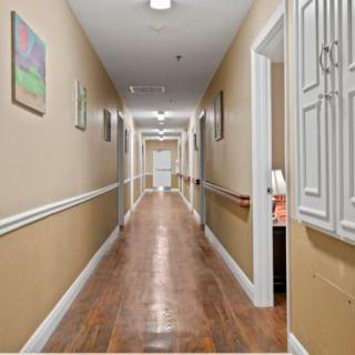 A long hallway with wooden floors and paintings on the walls.