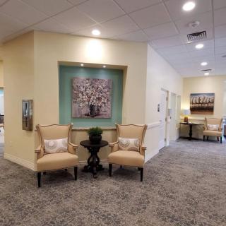 A comfortable lobby area featuring two chairs, artwork, and a carpeted hallway.