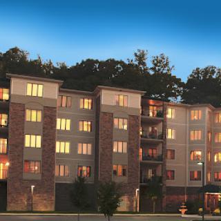 A modern apartment building illuminated at dusk, showcasing its architectural features and inviting atmosphere.