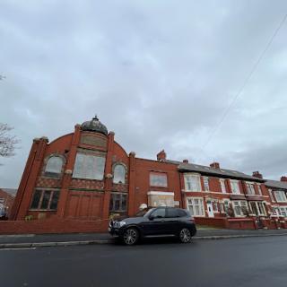 A view of a distinctive building adjacent to residential homes on a cloudy day.