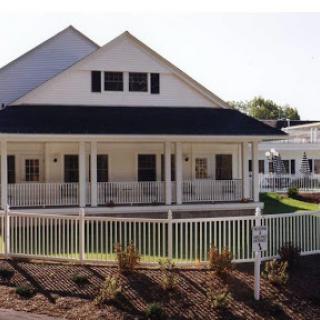 A charming white house featuring a spacious front porch and well-maintained landscaping.