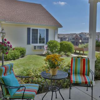 A cozy patio setup with colorful chairs and a table overlooking a well-maintained garden.
