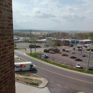 A view of a bustling urban area with a parking lot and various vehicles on the road.