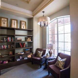 A cozy reading corner with armchairs and a bookshelf in a well-lit room.