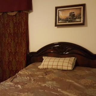 A cozy bedroom with a neatly made bed, decorated pillow, and artwork on the wall.