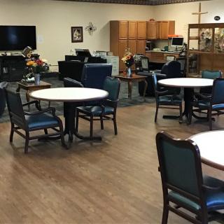 A community dining and recreation space with tables and chairs arranged in a cozy setting.
