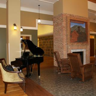 A cozy living room featuring a grand piano and a fireplace with comfortable seating.