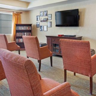 A cozy living room with multiple chairs facing a television and a bookshelf in the corner.