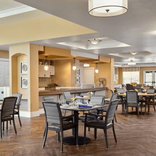 A spacious dining area with neatly arranged tables and comfortable seating, featuring warm lighting and modern decor.