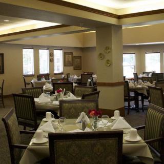 A well-set dining area with neatly arranged tables and chairs, featuring elegant decor and soft lighting.
