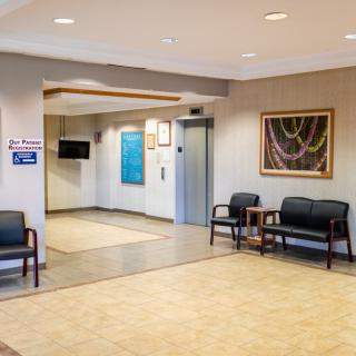A modern waiting area featuring comfortable seating, artwork, and an elevator.