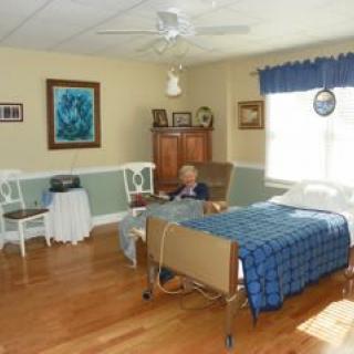An elderly person is resting in a healthcare room with medical equipment and comfortable furnishings.