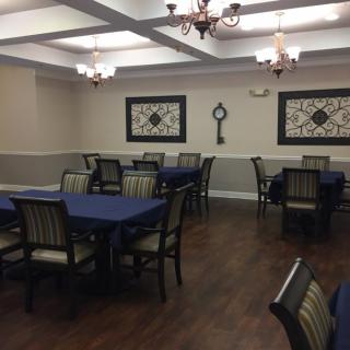 A well-decorated dining room with tables covered in blue tablecloths and elegant chandeliers hanging from the ceiling.