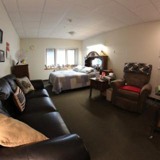 A cozy room featuring a bed, sofa, and armchair with soft lighting.