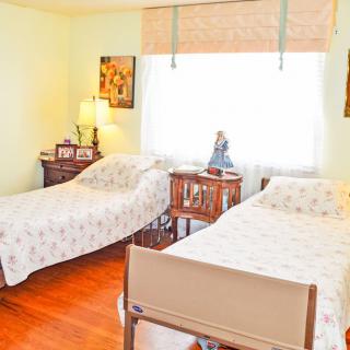 A cozy bedroom with two single beds, decorated with floral bedspreads and a lamp on a wooden nightstand.