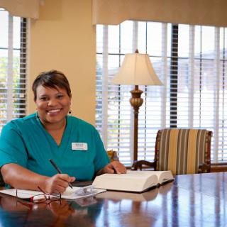 A healthcare professional smiles while working at a desk in a well-lit office environment.