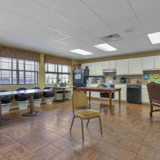 A spacious kitchenette with tables, chairs, and appliances.