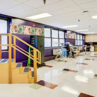 A spacious rehabilitation clinic with therapy equipment and stairs for physical exercises.
