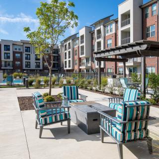 A modern apartment complex with outdoor seating and landscaped surroundings on a sunny day.