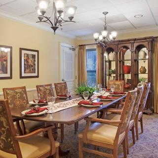 A beautifully decorated dining room with a chandelier, large wooden table, and matching chairs.