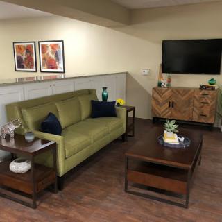 A cozy living room setup featuring a green sofa, wooden furniture, and decorative elements.